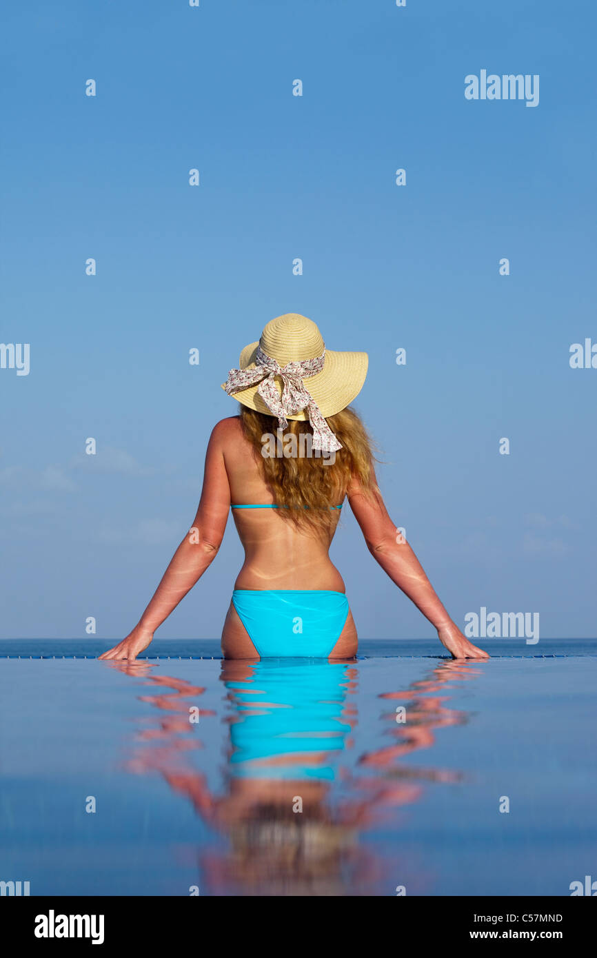 Femme assise dans la piscine à débordement Banque D'Images