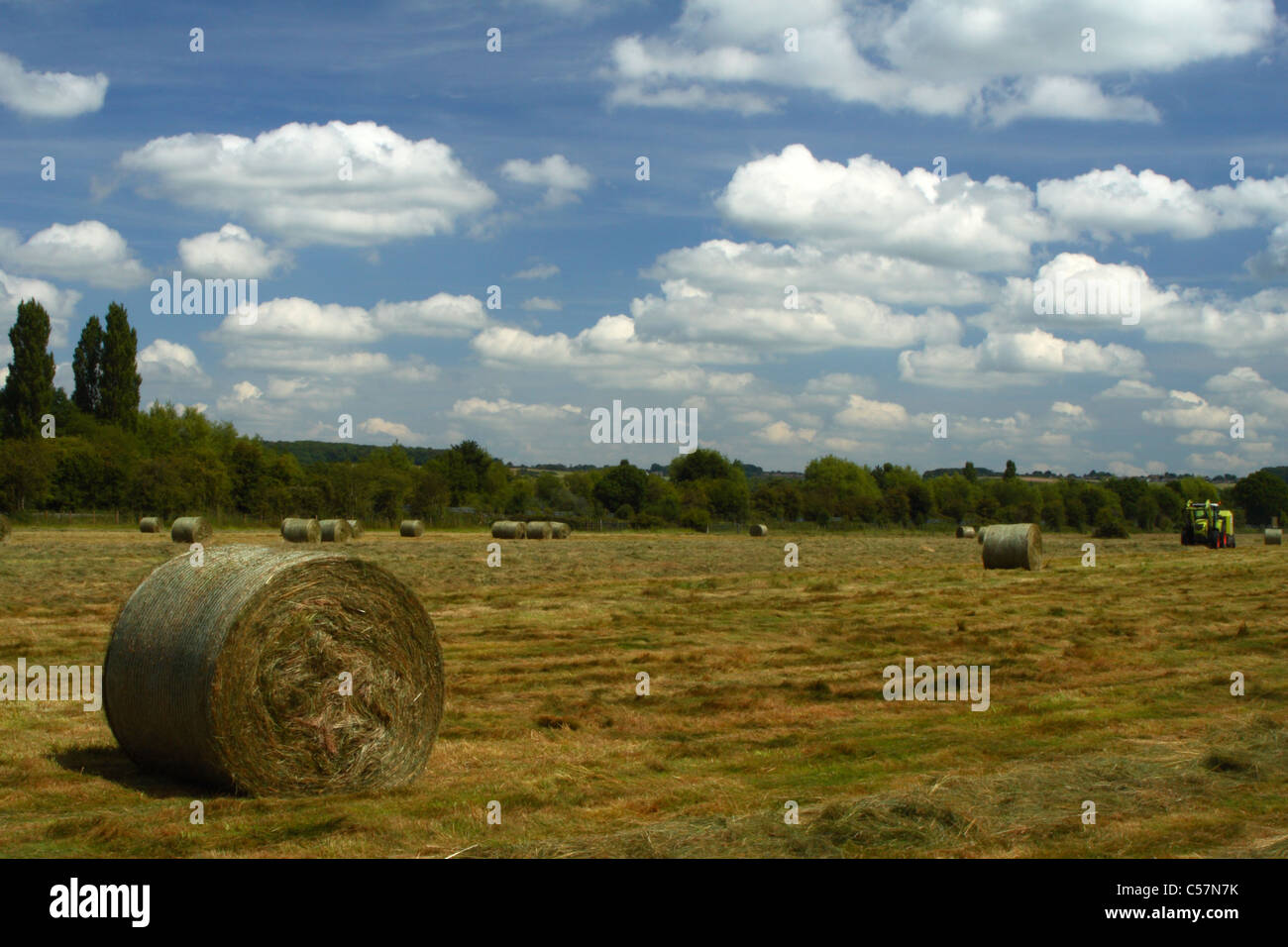 Une presse à balles de foin d'un champ de travail du tracteur à Bourne End, Buckinghamshire, Royaume-Uni Banque D'Images