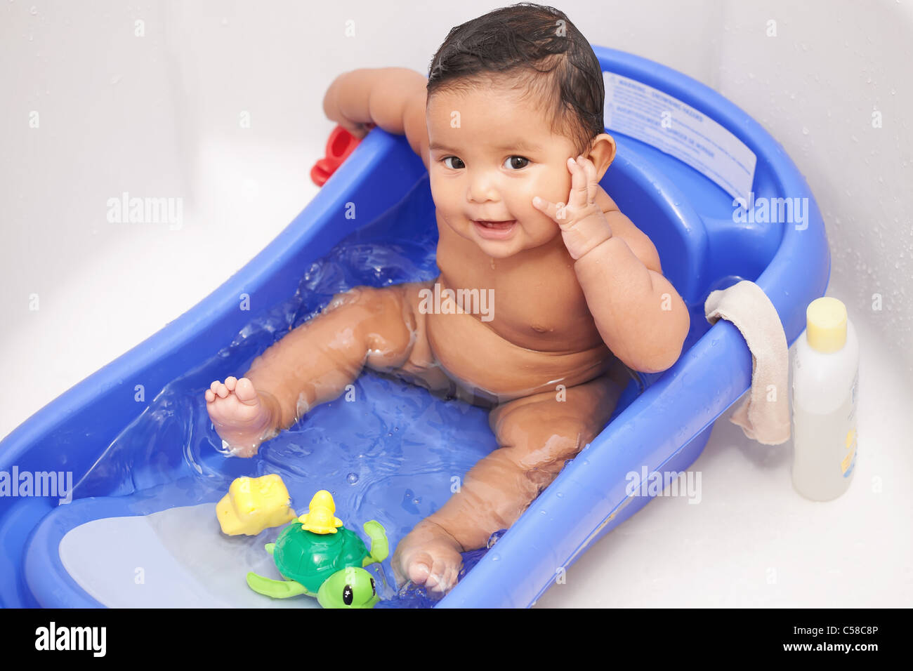 Happy baby girl sitting en toute sécurité dans une baignoire pour bébé avec jeux  d'eau et laver le linge prêt à être nettoyé Photo Stock - Alamy