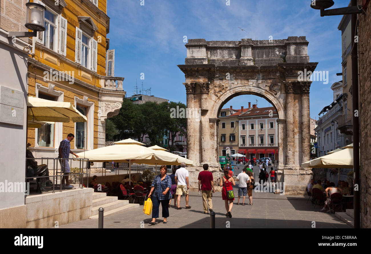 Les piétons traversant la Zlata Vrata (Golden Gate) de Pula en Croatie. Autrement connu comme l'Arc de Sergius. Banque D'Images Les piétons traversant la Zlata Vrata (Golden Gate) de Pula en Croatie. Autrement connu comme l'Arc de Sergius. Banque D'Images