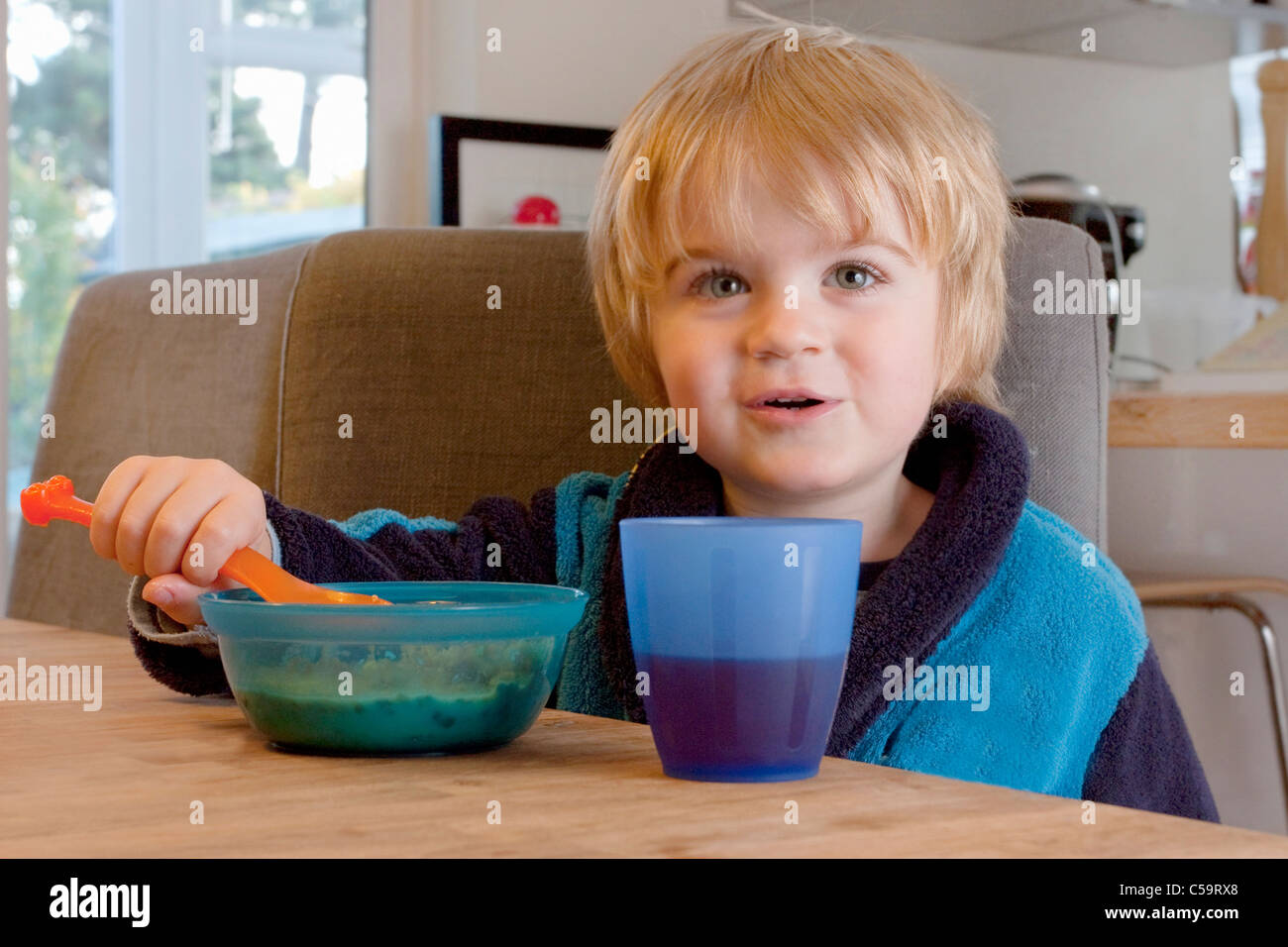 Petit garçon de manger les céréales petit déjeuner dans la cuisine et souriant Banque D'Images