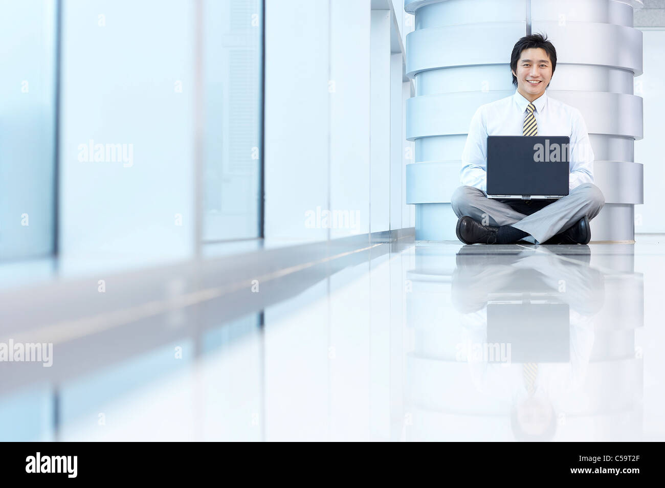 Portrait of businessman sitting par pilier, using laptop Banque D'Images