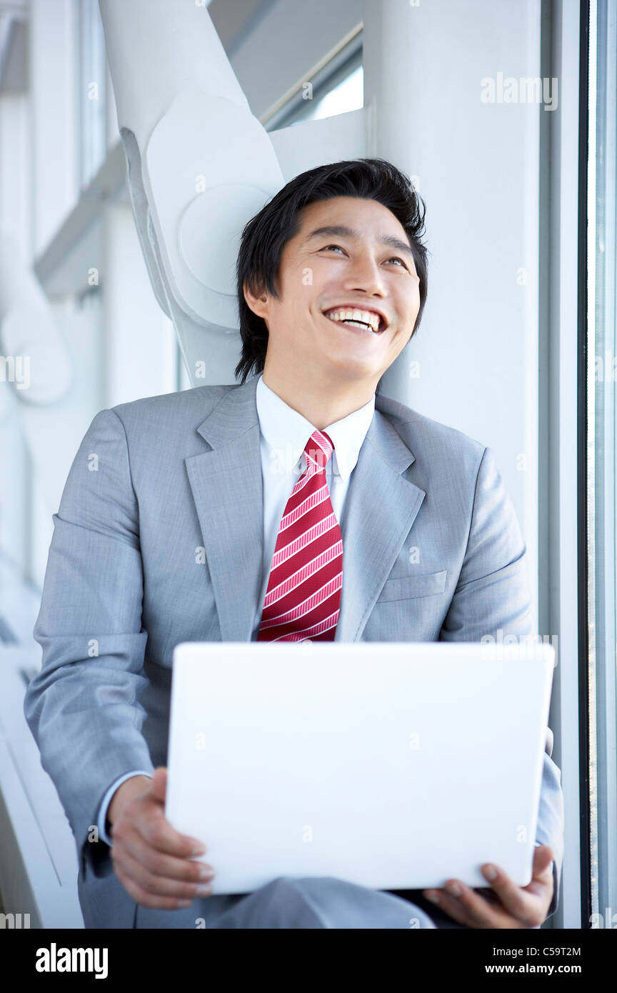 Close-up of businessman smiling while using laptop Banque D'Images