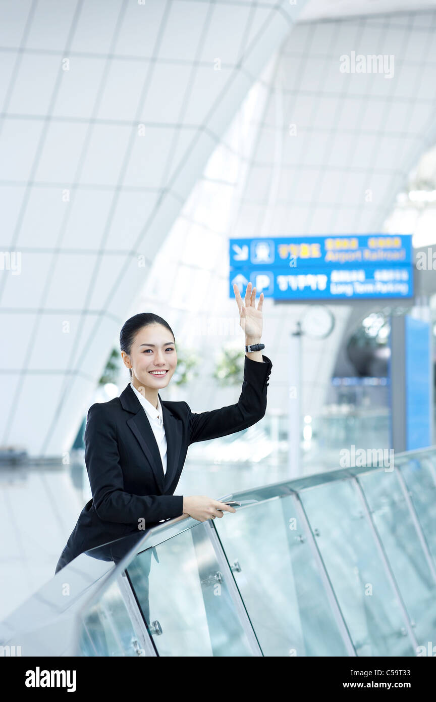 Vue latérale du businessman waving sur terminal de l'aéroport Banque D'Images