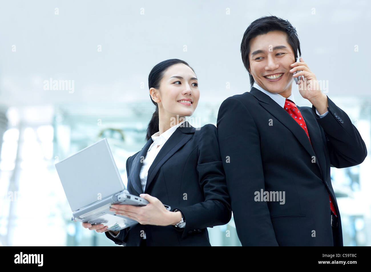 Vue latérale du businessman talking on mobile phone while businesswoman holding laptop Banque D'Images