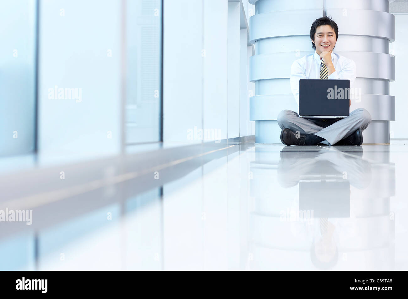 Portrait of businessman sitting par pilier, using laptop Banque D'Images