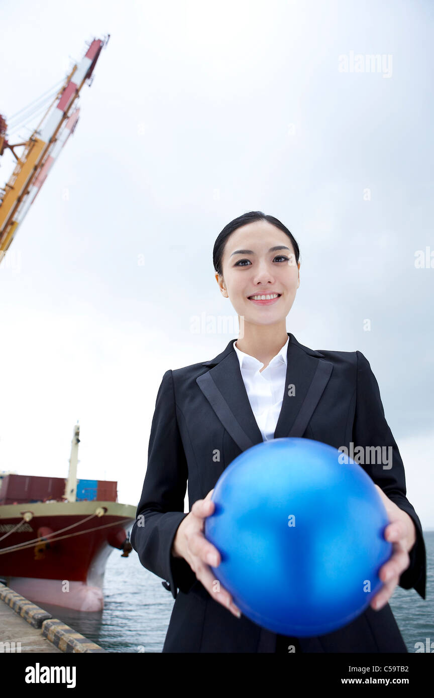 Portrait of businesswoman holding blue ball Banque D'Images