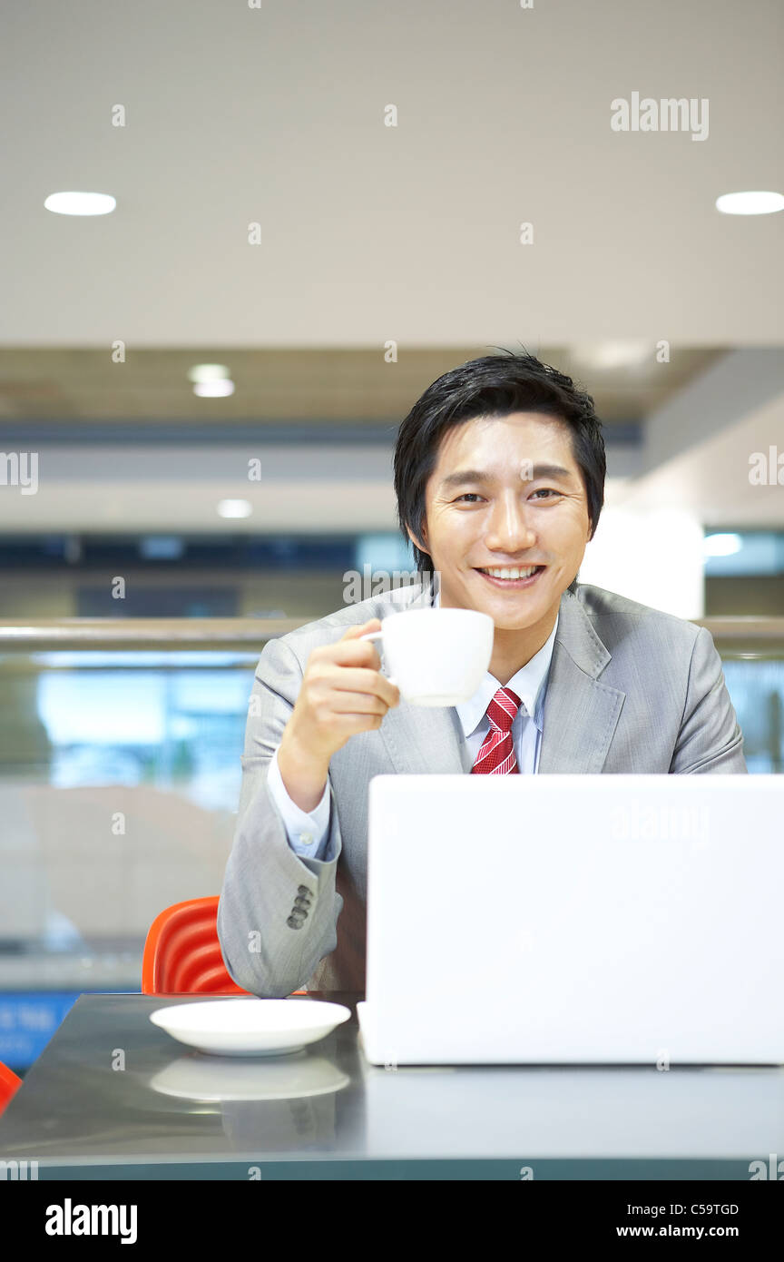Portrait of businessman with Cup and Saucer using laptop Banque D'Images