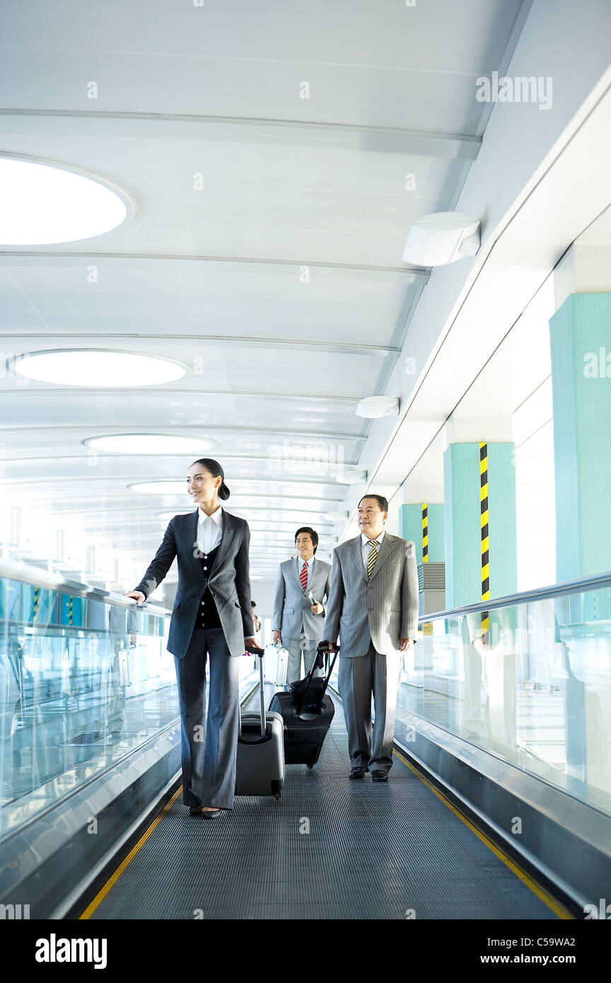 Businesspeople walking avec les bagages à l'aéroport Banque D'Images