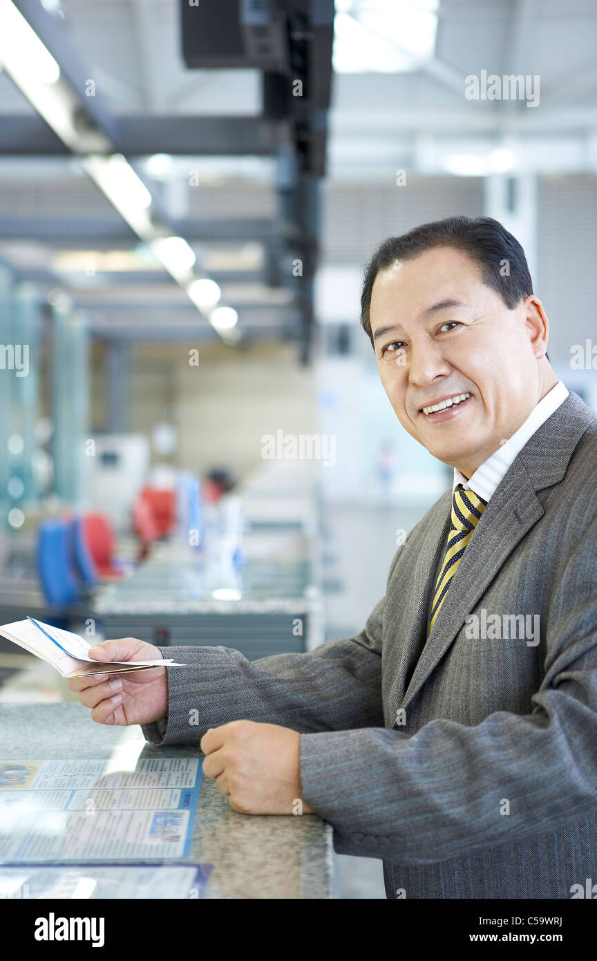 Portrait of businessman holding passeport et le billet au comptoir Banque D'Images