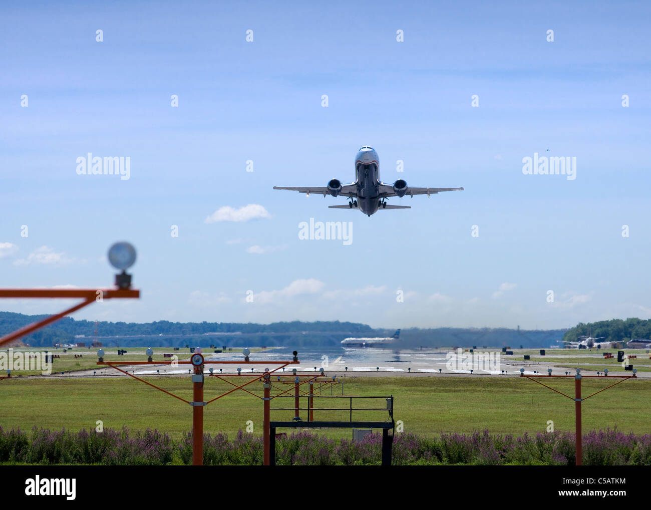 Un jet de banlieue enlève plus de PAPI les lumières à la fin de la piste Banque D'Images