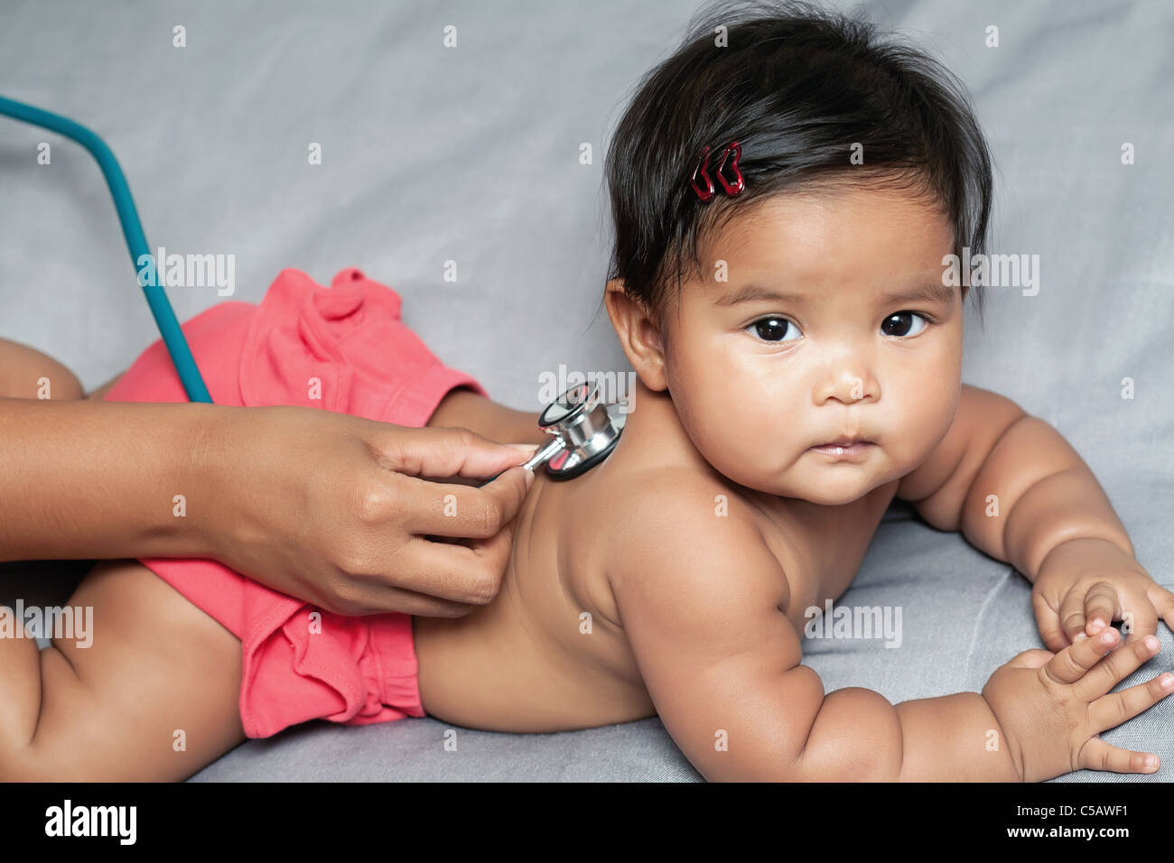 Baby Girl portant sur son ventre, infirmière's hand holding stethoscope écouter les poumons au cours de check up Banque D'Images