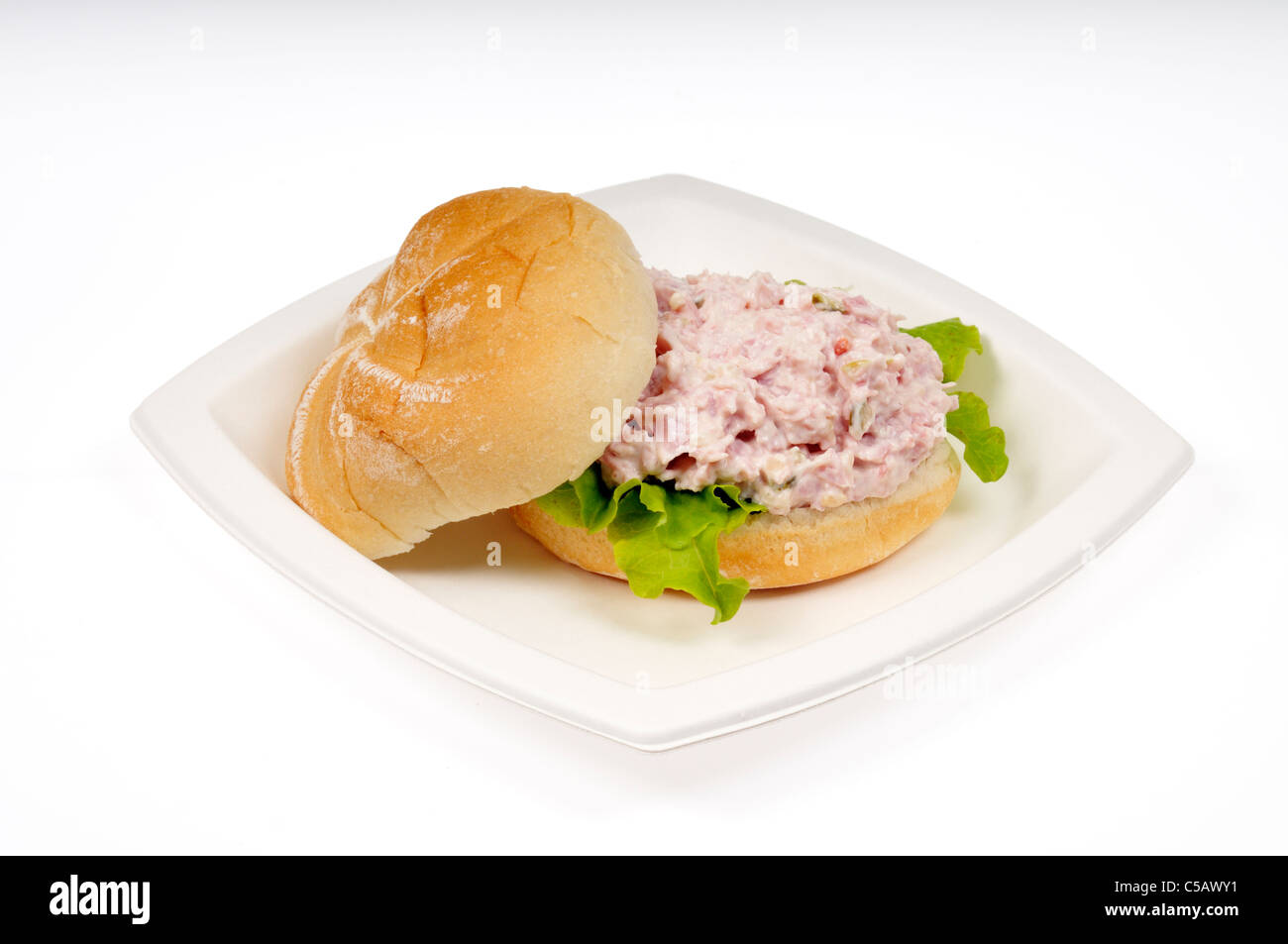 Sandwich à la salade de jambon avec de la laitue dans un rouleau sur plaque blanche sur fond blanc, cut out. Banque D'Images