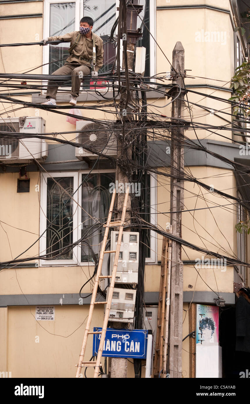 Réparateur sur lignes électriques à l'intersection de Bat Dan St et St peut accrocher vieux quartier de Hanoi, Vietnam Banque D'Images