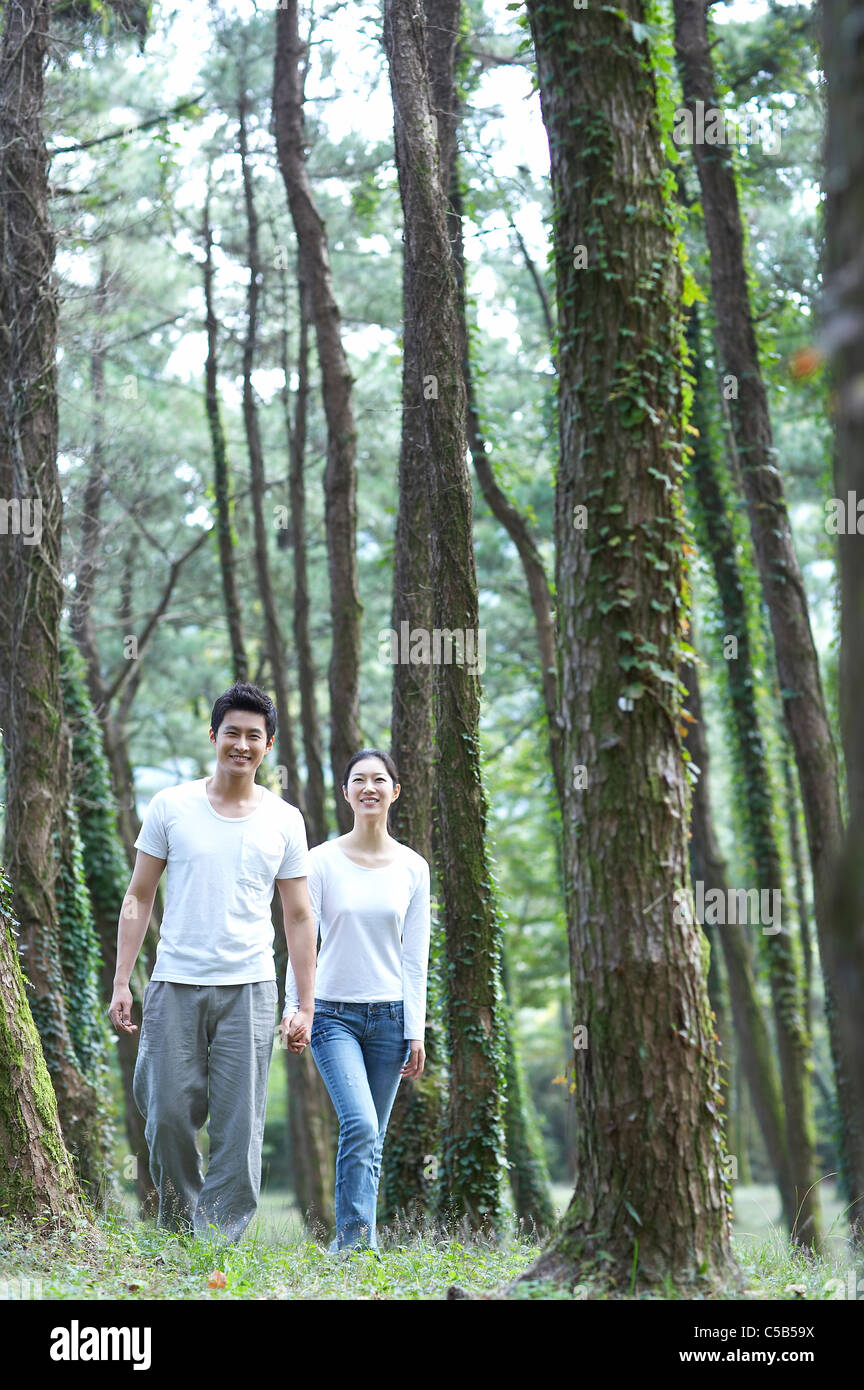 Couple holding hands walking through forest Banque D'Images