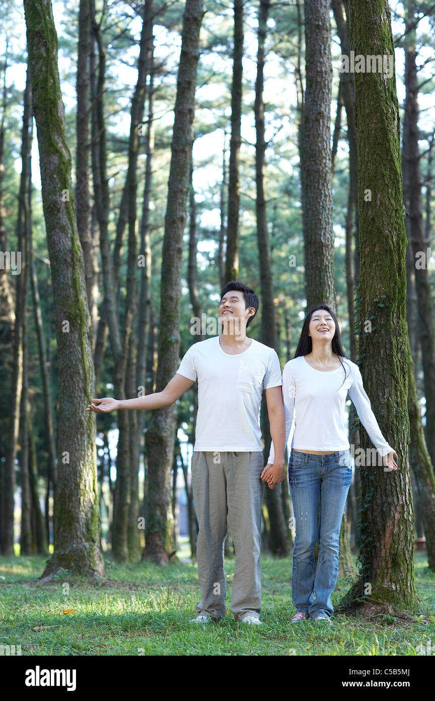 Couple holding hands walking through forest, Banque D'Images