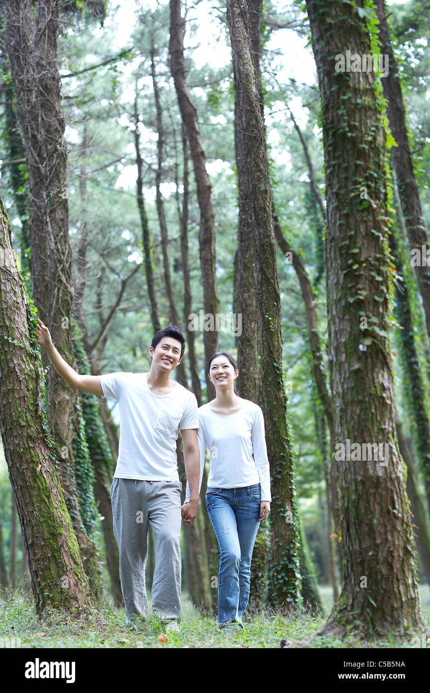 Couple holding hands walking through forest, Banque D'Images