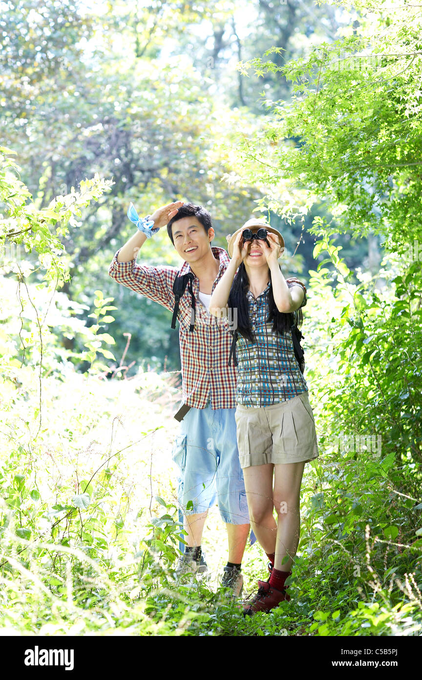 En couple à la recherche forestière dans les jumelles, Banque D'Images