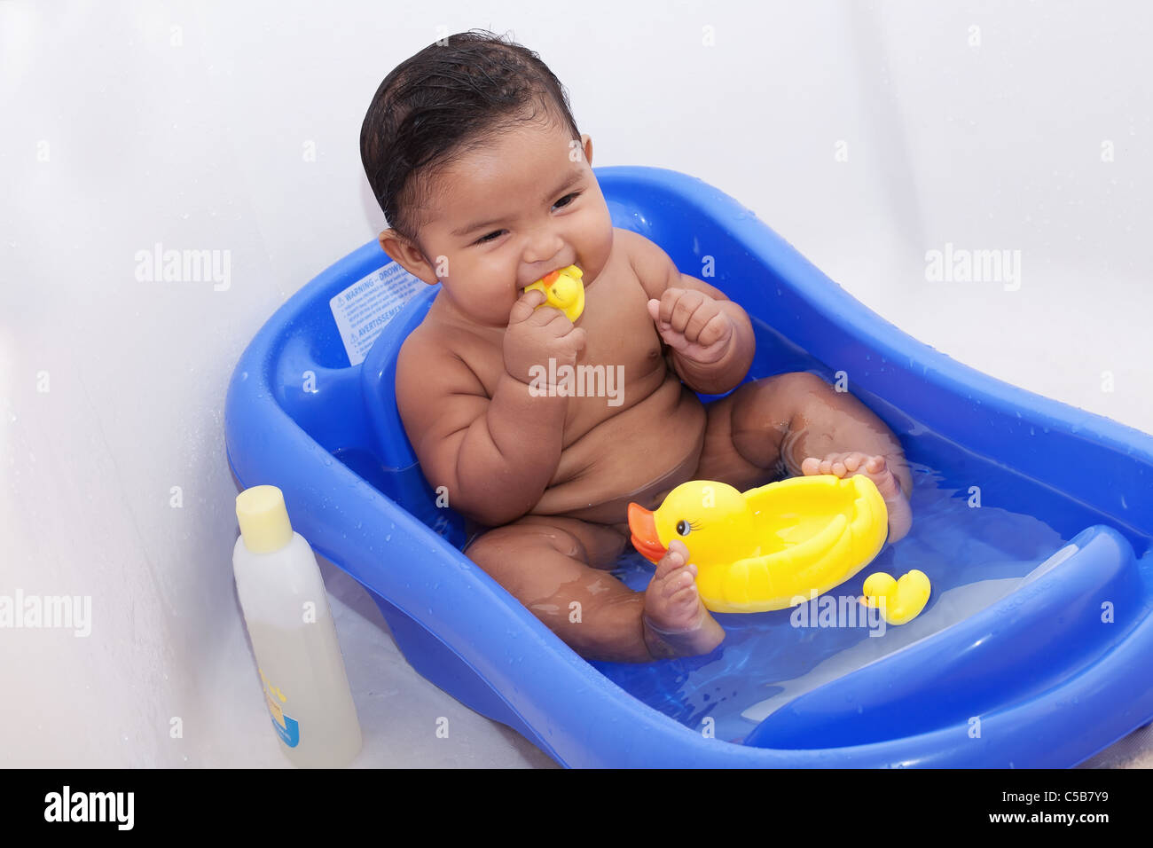 Bébé jouant avec des canards en caoutchouc dans la baignoire Banque D'Images