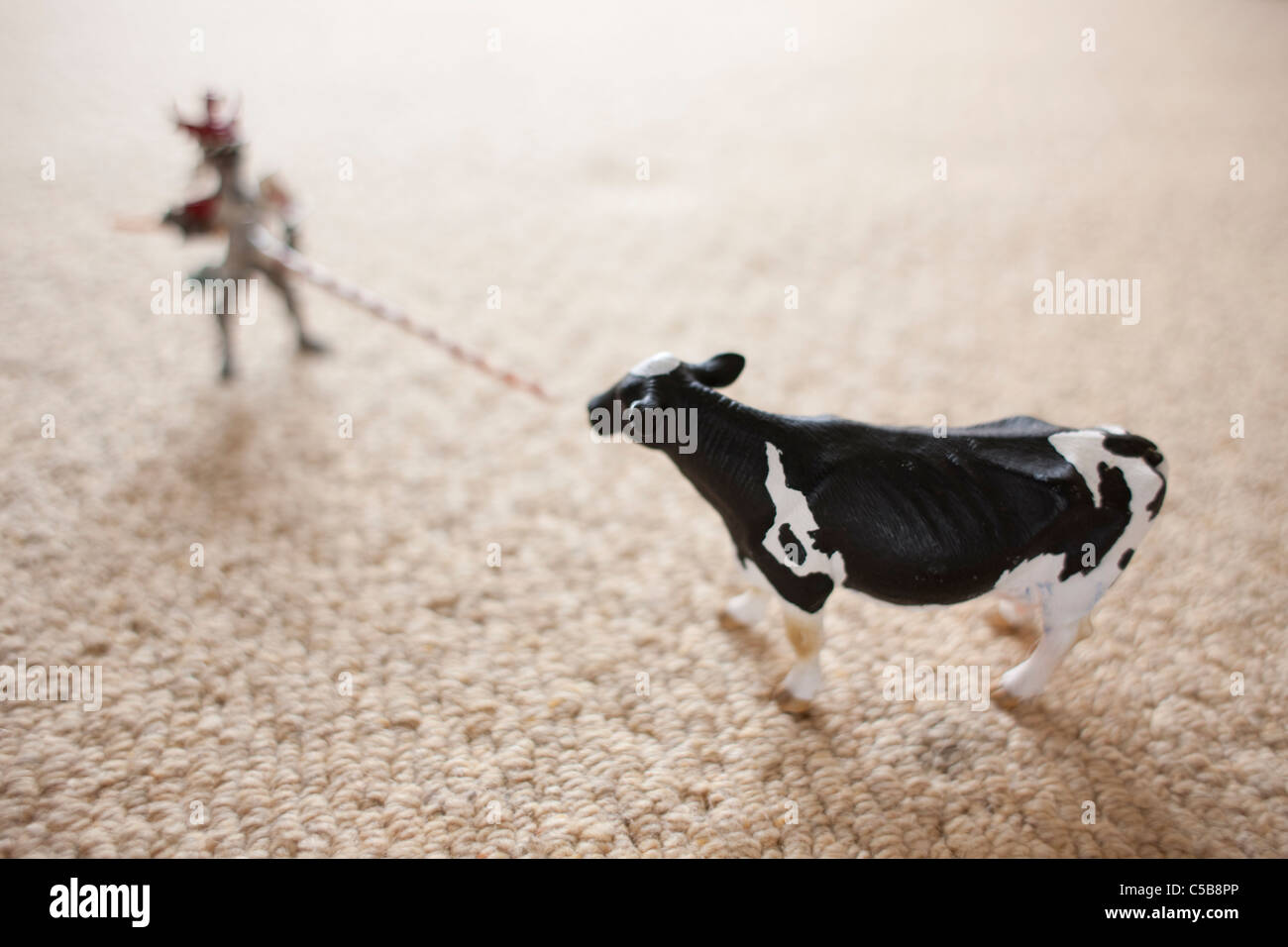 Vache jouet et figure sur la moquette Banque D'Images