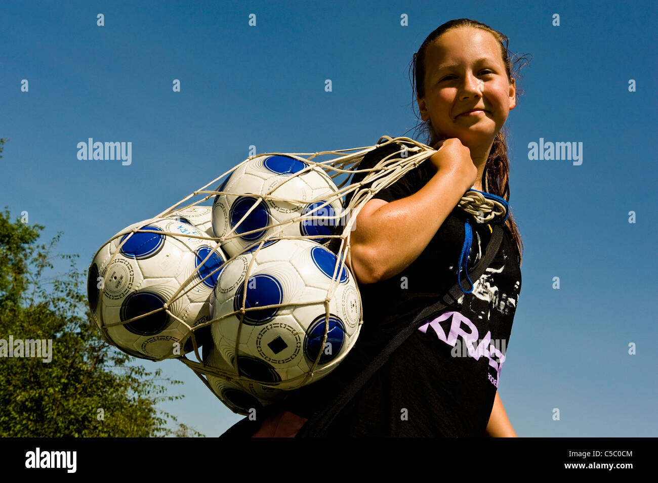 Low angle view of a smiling girl avec ballons dans un sac filet contre ciel bleu clair Banque D'Images