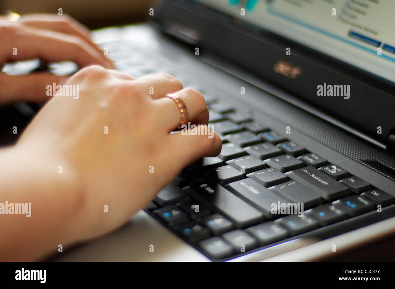 Femme de la saisie sur ordinateur portable avec bouton de retour arrière dans l'accent, sur l'anneau celtique doigt main droite. Banque D'Images