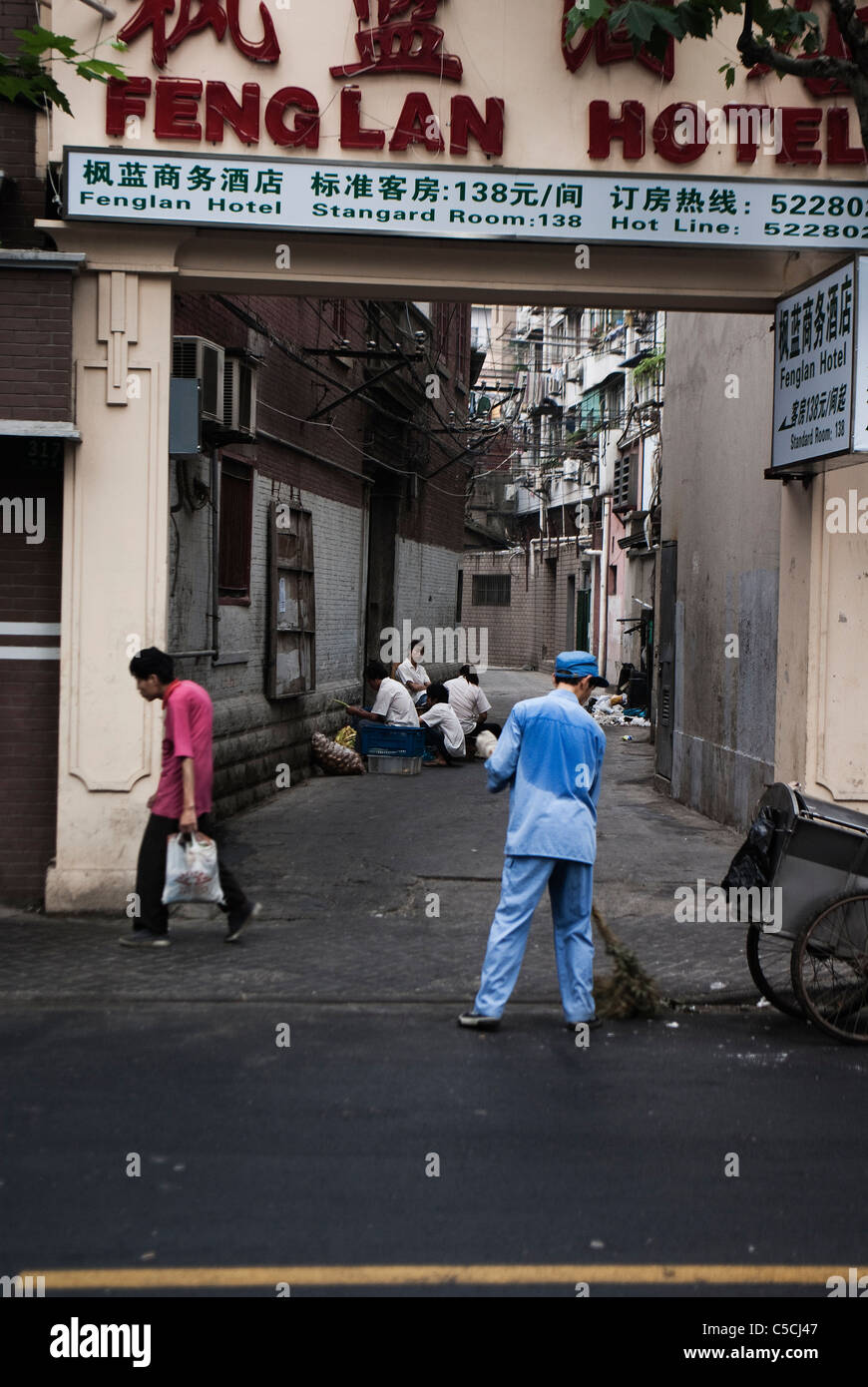 Nettoyant de la rue et la femme avec la butte en face d'un hotel à Shanghai, Chine Banque D'Images