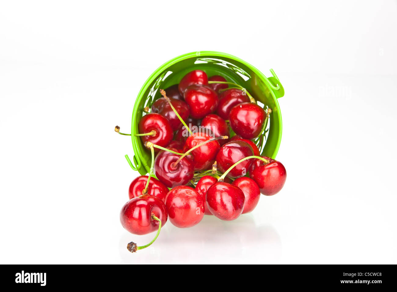 Cerises rouges frais dans un bol vert sur fond blanc Banque D'Images