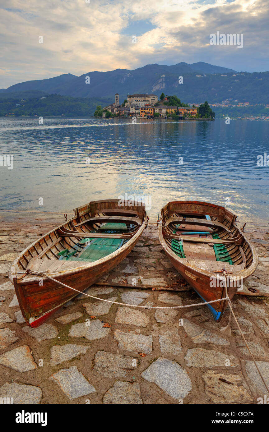 L'île de San Giulio sur le lac d'Orta avec deux vieux bateaux en bois au premier plan Banque D'Images