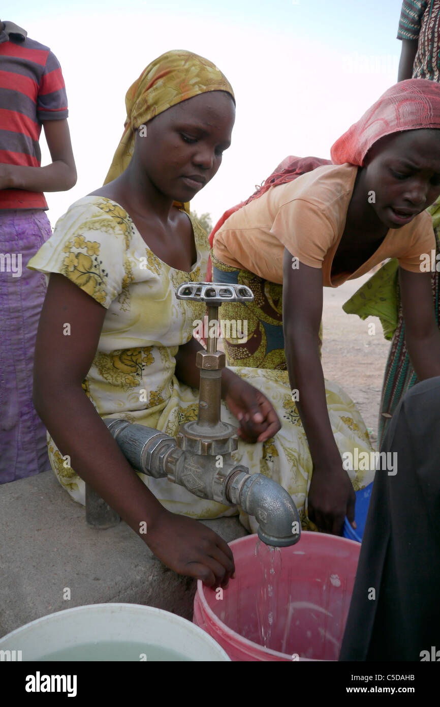 Tanzanie Village d'Mwamalasa, Shinyanga. La collecte de l'eau d'un réservoir de stockage. L'eau est pompée par les éoliennes dans le réservoir. Banque D'Images