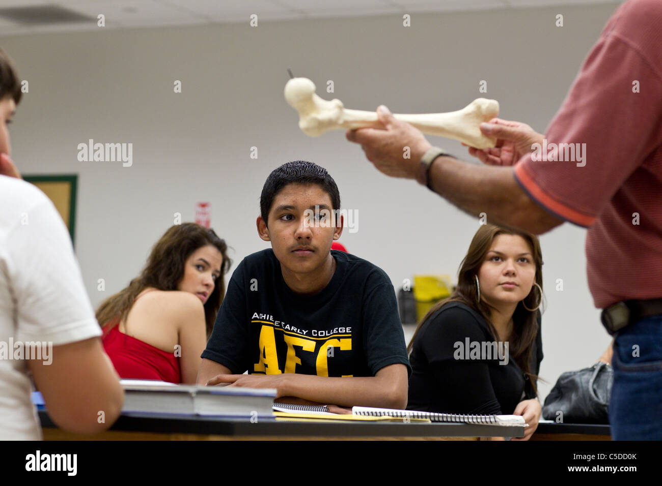 Enseignant de sexe masculin jusqu'moule en plastique d'un os comme une démonstration dans la classe de sciences à l'école secondaire du sud du Texas que les élèves écoutent Banque D'Images