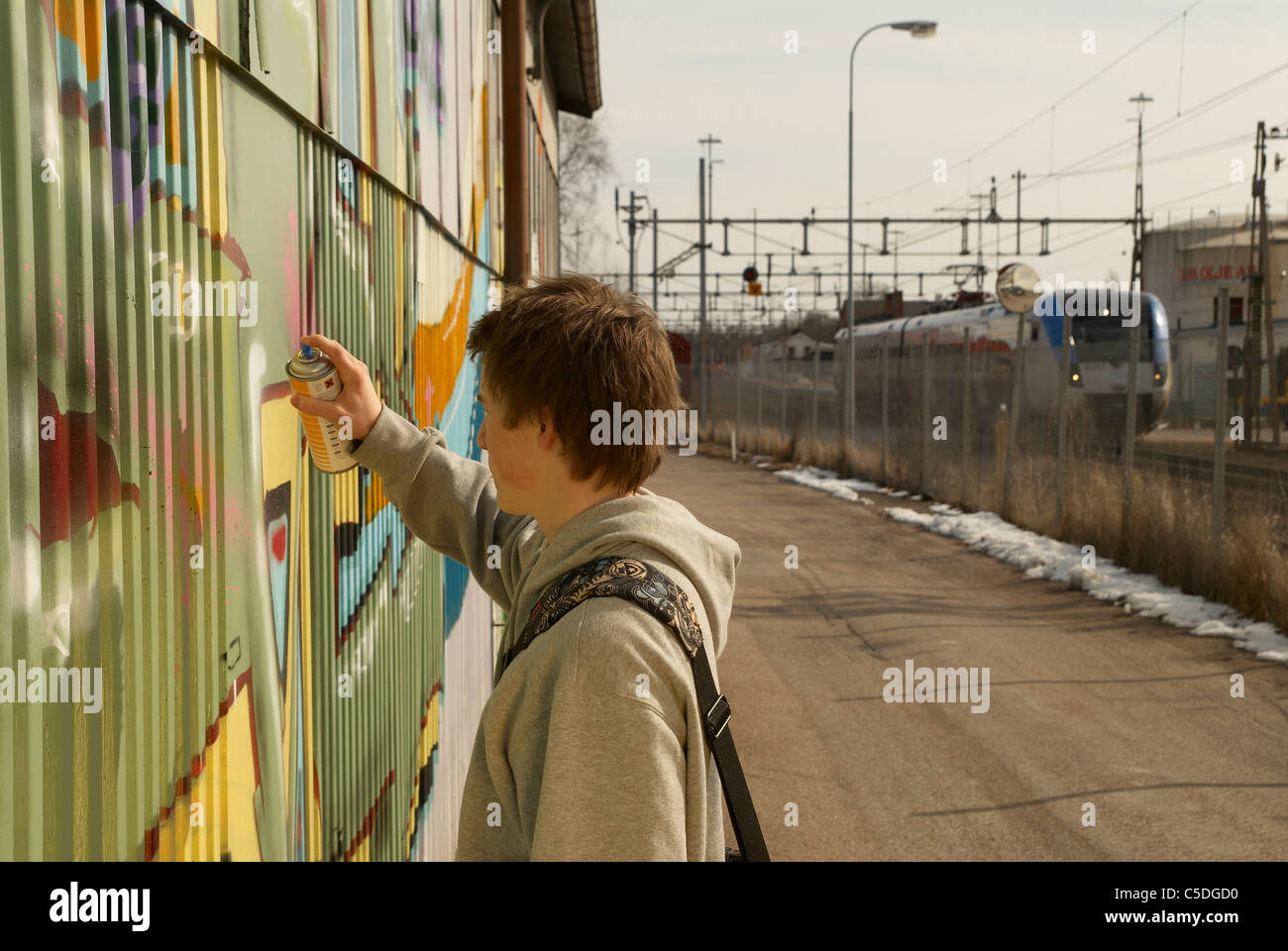 Vue latérale d'un adolescent sur le mur de graffiti de pulvérisation Banque D'Images