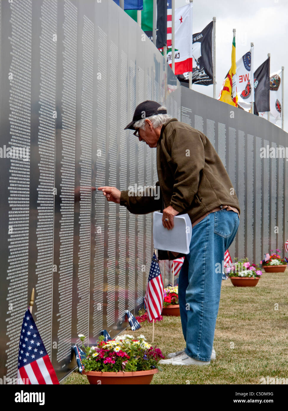 Un vétéran cherche un nom au mur qui guérit, une réplique de la moitié de l'échelle de la Vietnam Veterans Memorial. Banque D'Images