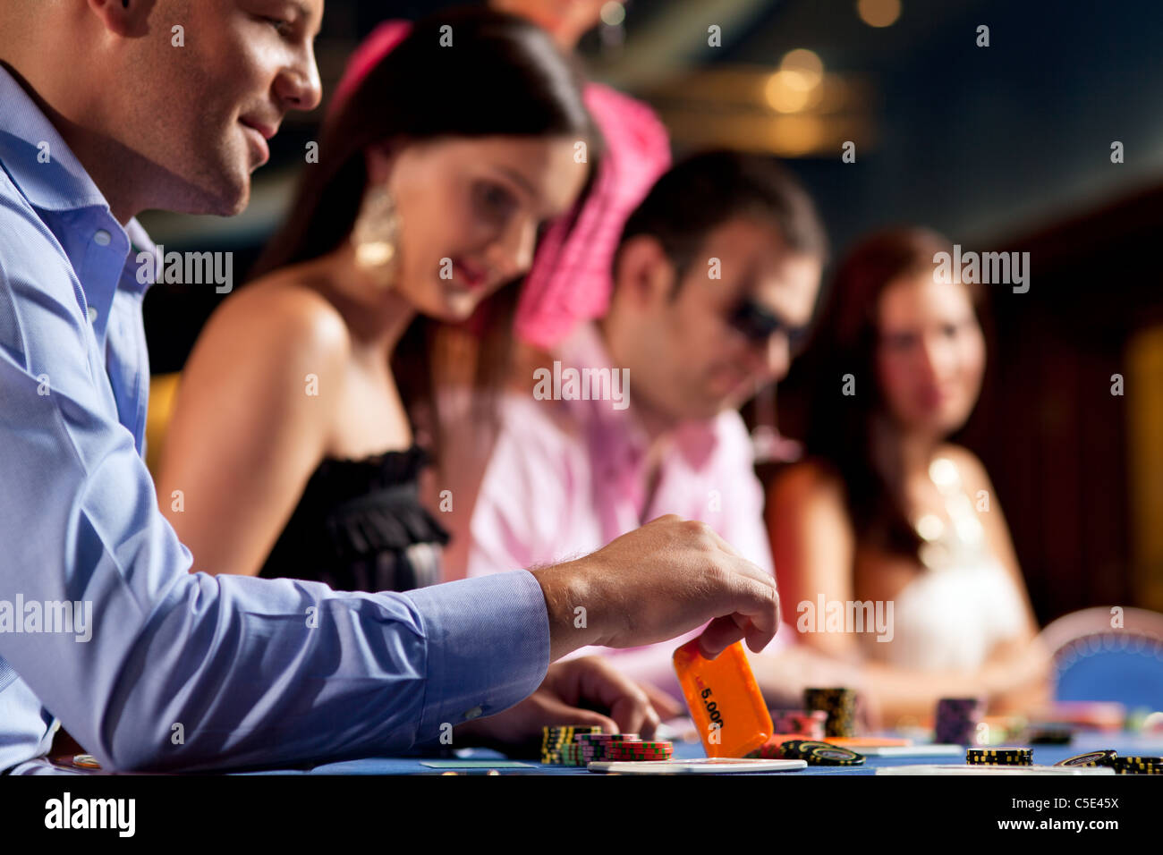 Les joueurs de poker à la table, l'homme tenant une carte de cinq mille Banque D'Images