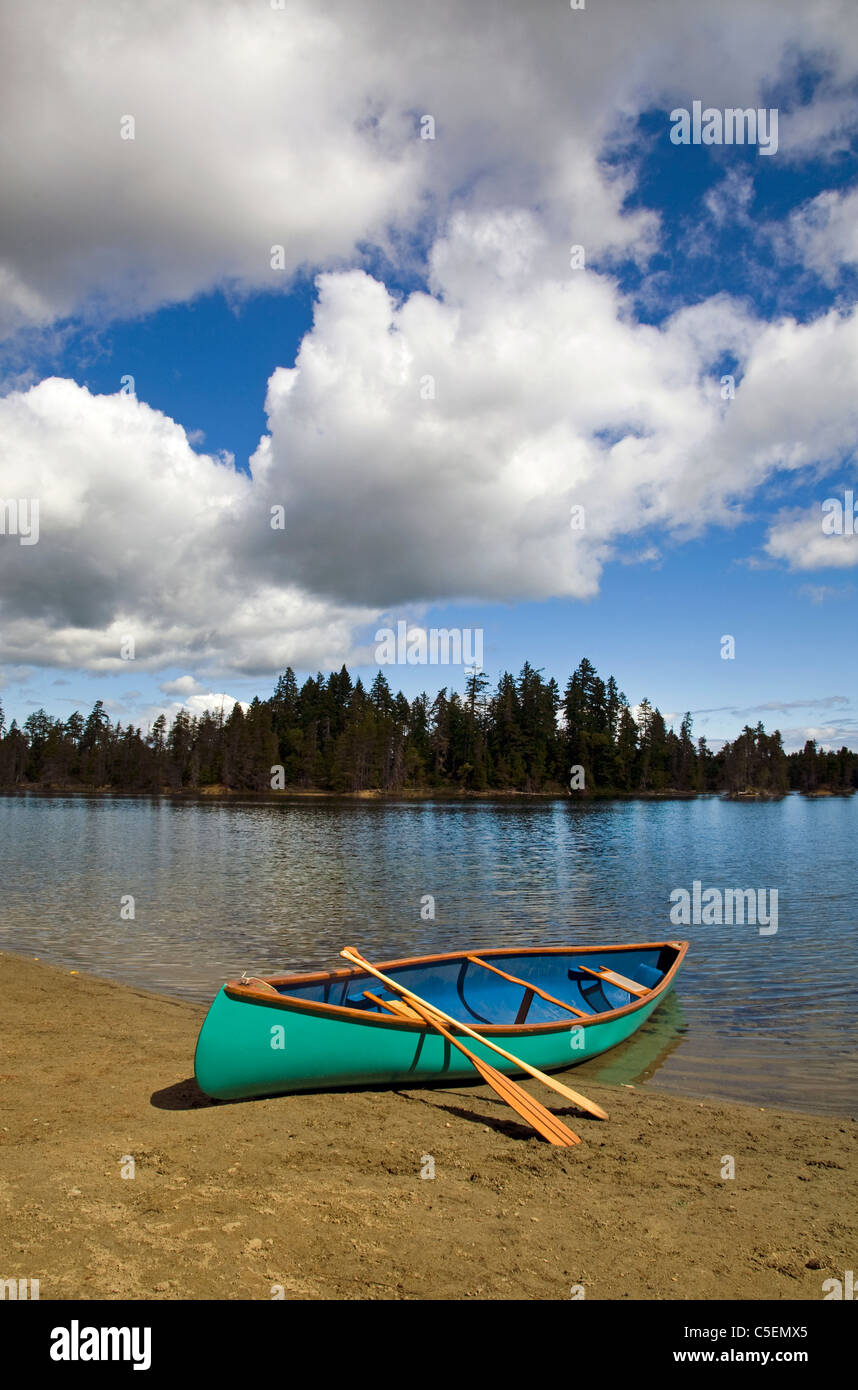 Un canoë et des pagaies sur la rive d'un lac de montagne, l'île de Vancouver, Colombie-Britannique, Canada. Banque D'Images