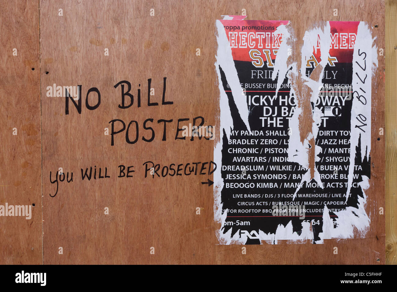 Un projet de loi sans avertissement des affiches indiquent un poster déchiré collé à un chantier de construction temporaire plyboard mur. Banque D'Images