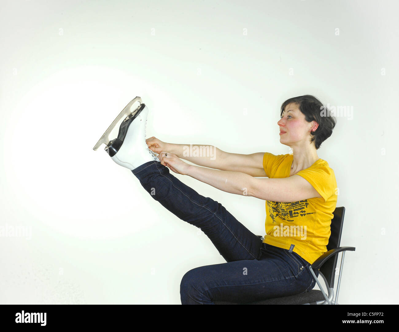 Une jeune femme de race blanche mettre sur un patin à glace, tenant sa jambe vers le haut pour attacher les lacets. Banque D'Images