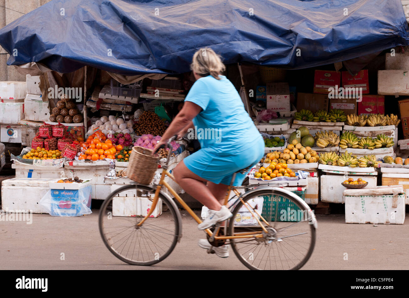 Grosses Femmes sur une bicyclette au-delà d'un étal de fruits, Siem Reap, Cambodge Banque D'Images