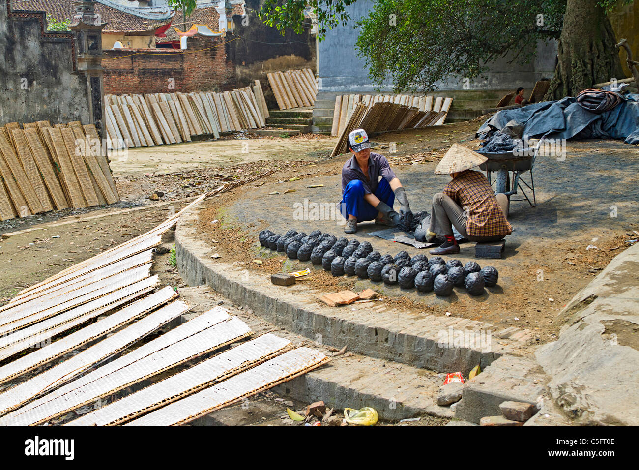 Papier de Riz (utilisé en cuisine) sèche sur des supports alors que les travailleurs de "ruche" du charbon dans Tho Ha village, sur une petite île près de Hanoi Banque D'Images