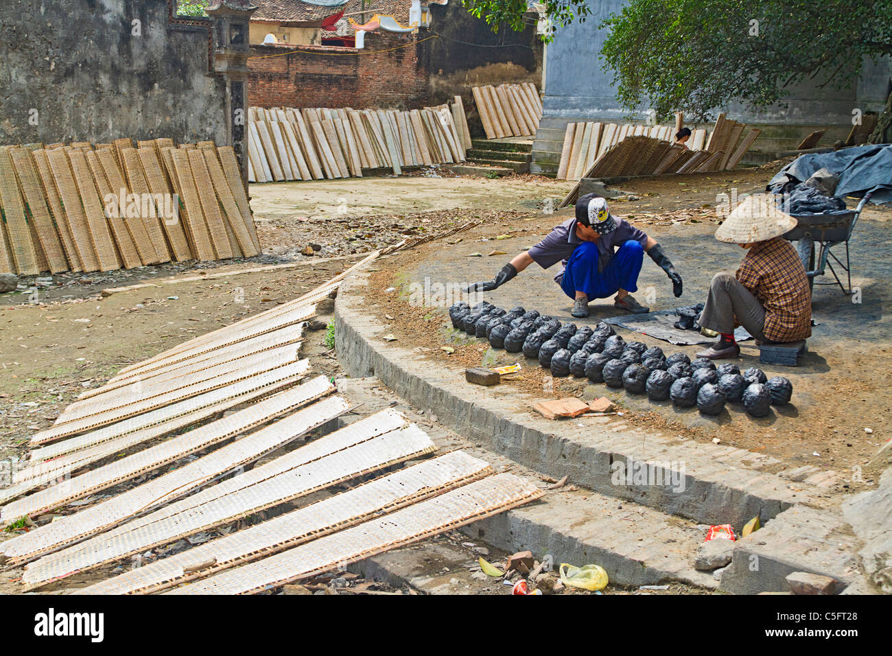 Papier de Riz (utilisé en cuisine) sèche sur des supports alors que les travailleurs de "ruche" du charbon dans Tho Ha village, sur une petite île près de Hanoi Banque D'Images
