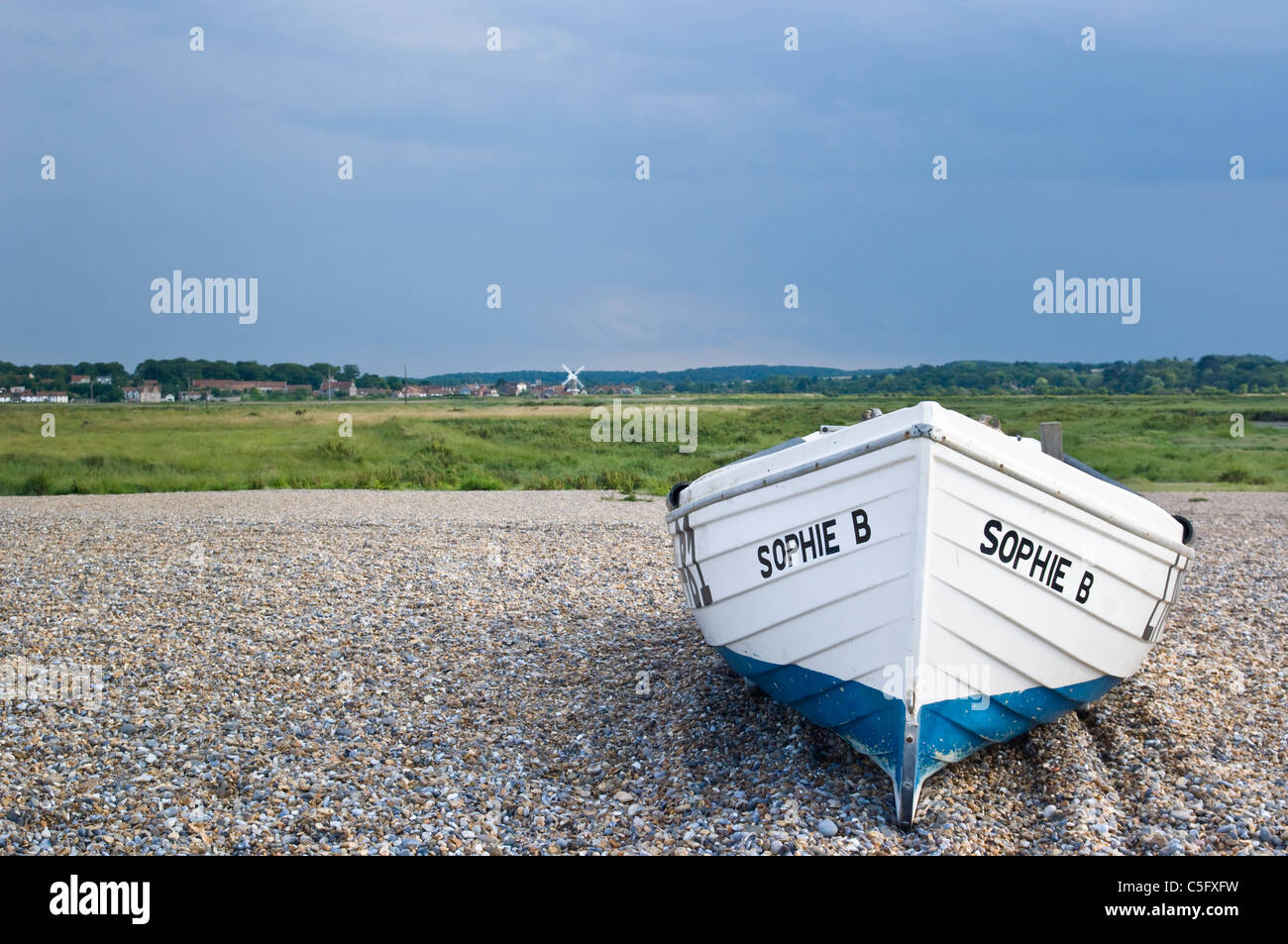 Voile sur la plage de galets à Claj-next-the-Sea, Norfolk, UK, avec les marais de sel et moulin derrière le CLAJ et village de distance Banque D'Images