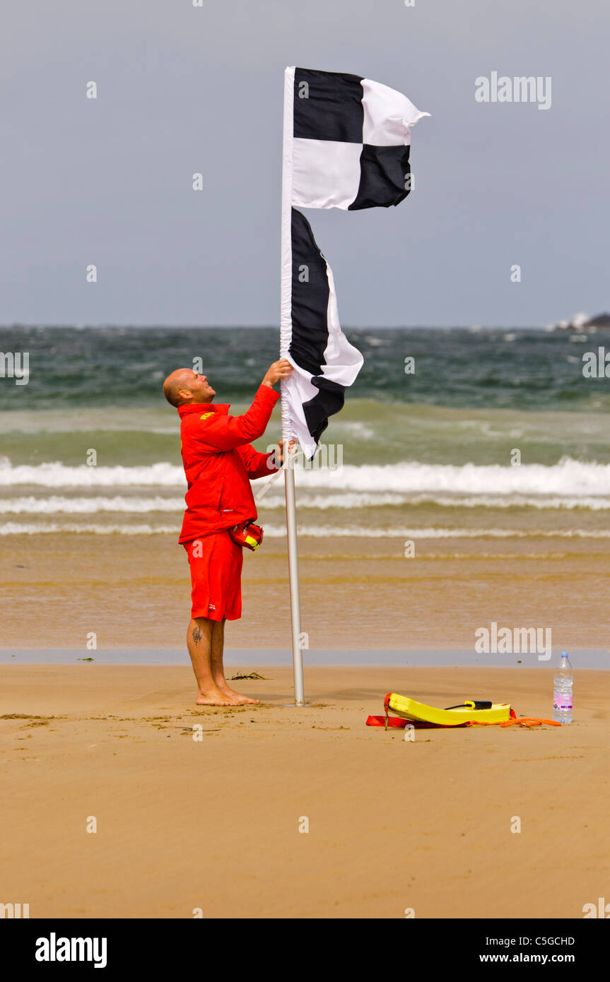 Sauveteur RNLI érige à carreaux noirs et blancs que les nageurs avertissement drapeau surfeurs les surfeurs et les kayaks sont dans la région Banque D'Images