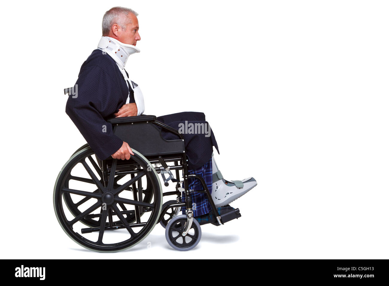 Photo d'un homme blessé se poussant le long de dans son fauteuil roulant, isolé sur un fond blanc. Banque D'Images