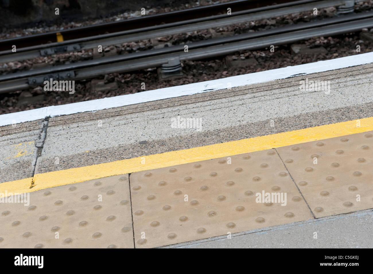 Peint en jaune ligne indiquant l'entrée de la surface où les passagers peuvent se tenir en toute sécurité sur une plate-forme en Angleterre. Banque D'Images