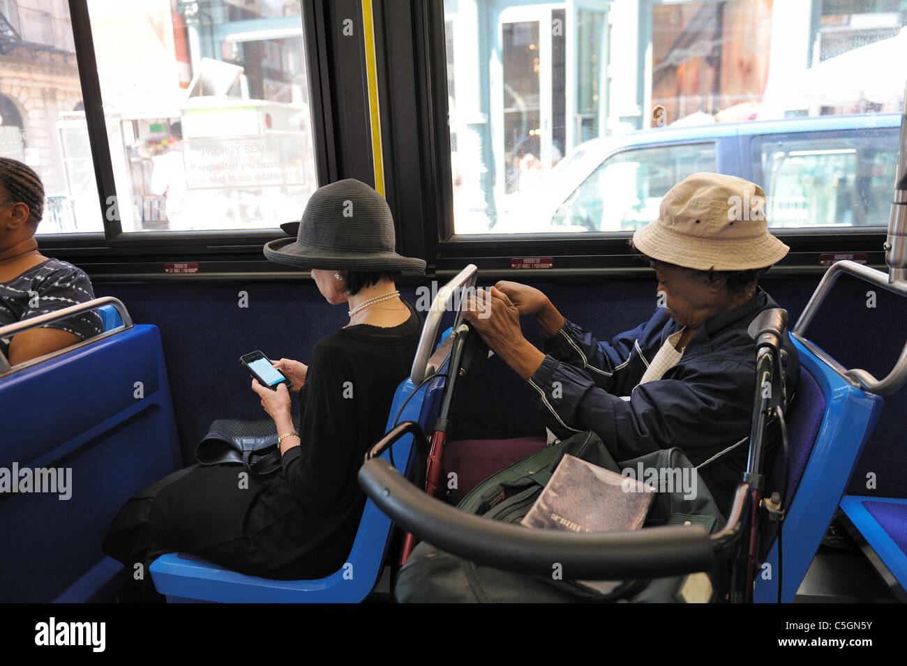 Une femme habillée coûteusement et pauvre avec une marchette et une Bible assis près de l'autre sur un bus de Manhattan. 20 juillet 2011 Banque D'Images