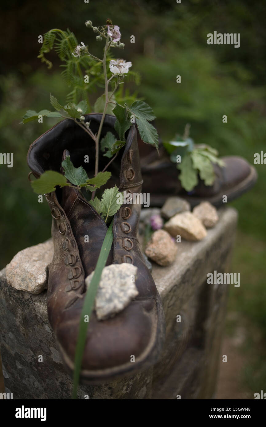 Vieilles bottes remplies de fleurs et plantes placé sur une borne dans le chemin de Saint-Jacques de Compostelle, Santiago de Compostela, Banque D'Images