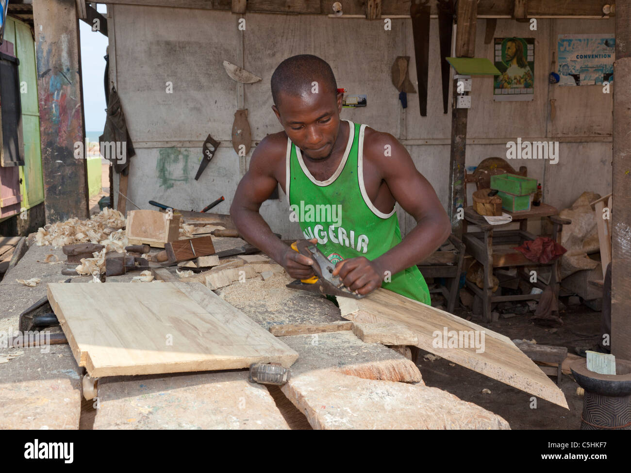 Un charpentier de la planification d'une pièce de bois pour construire un cercueil. Accra, Ghana Banque D'Images