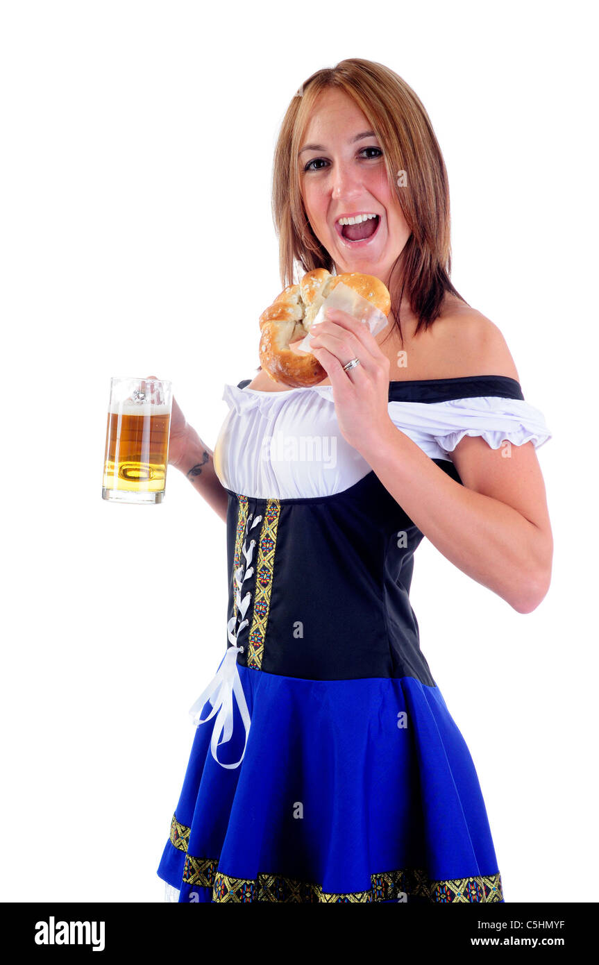 Belle femme portant un costume bleu traditionnel Oktoberfest Dirndl pour célébrations de manger un bretzel et tenant une bière Stein Banque D'Images