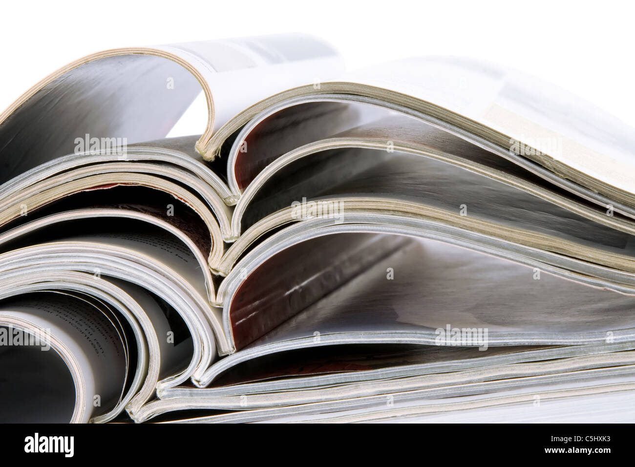 Pile de vieux magazines avec des pages de flexion sur fond blanc Banque D'Images