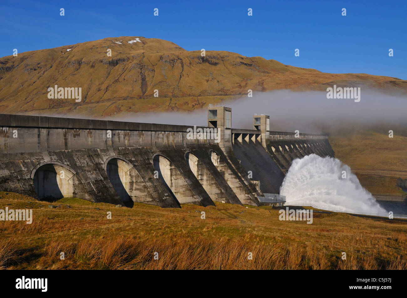 Glen Lyon barrage hydroélectrique de l'eau d'évacuation avec un arrière-plan de Misty Hills et ciel bleu, Perthshire, Écosse, Royaume-Uni. Banque D'Images